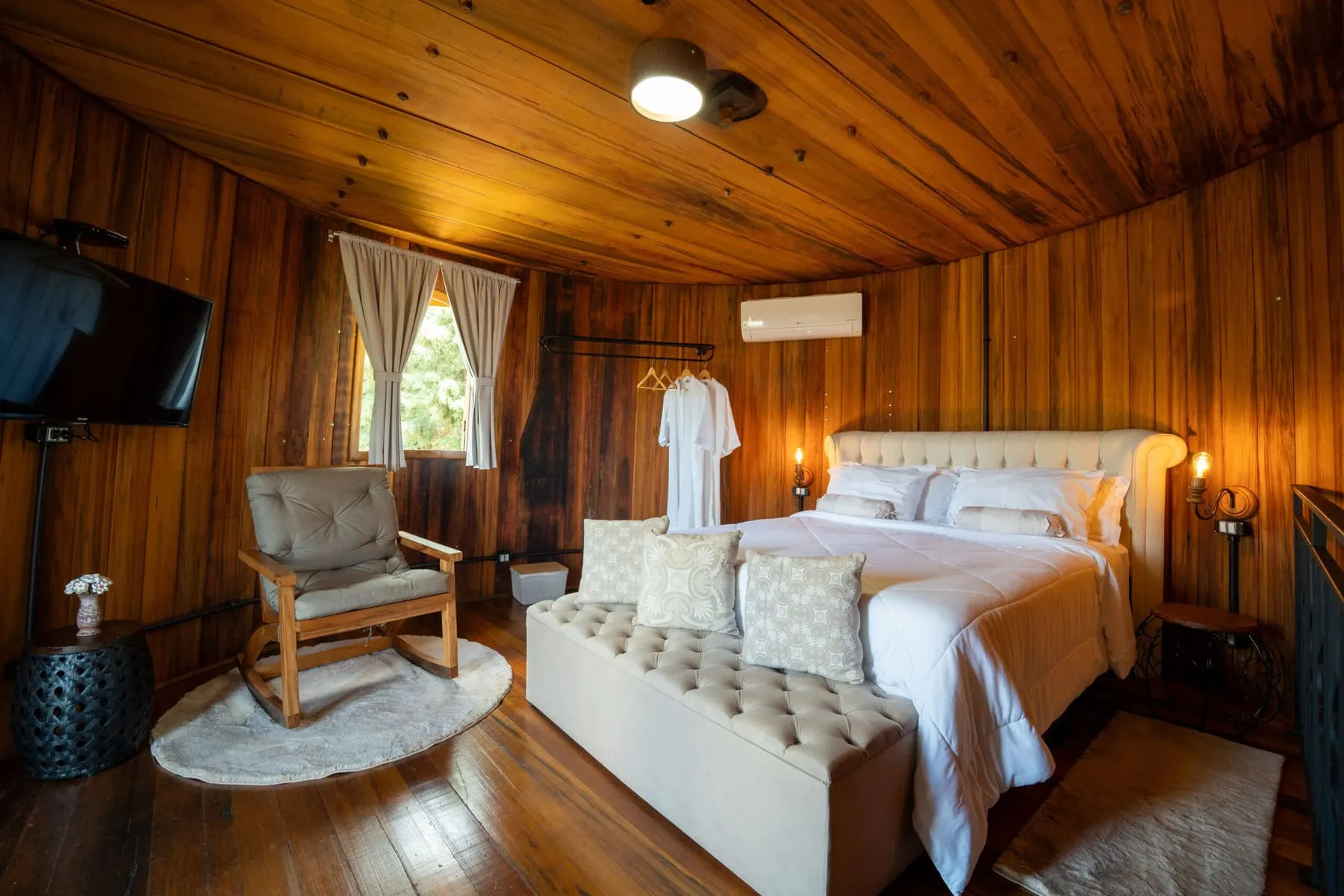 Interior aconchegante de um chalé de madeira, com cama e poltrona de balanço